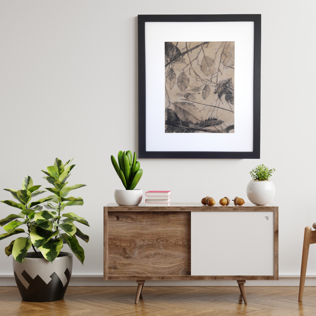 A photograph of a framed charcoal painting hanging on a white wall above a living room console.