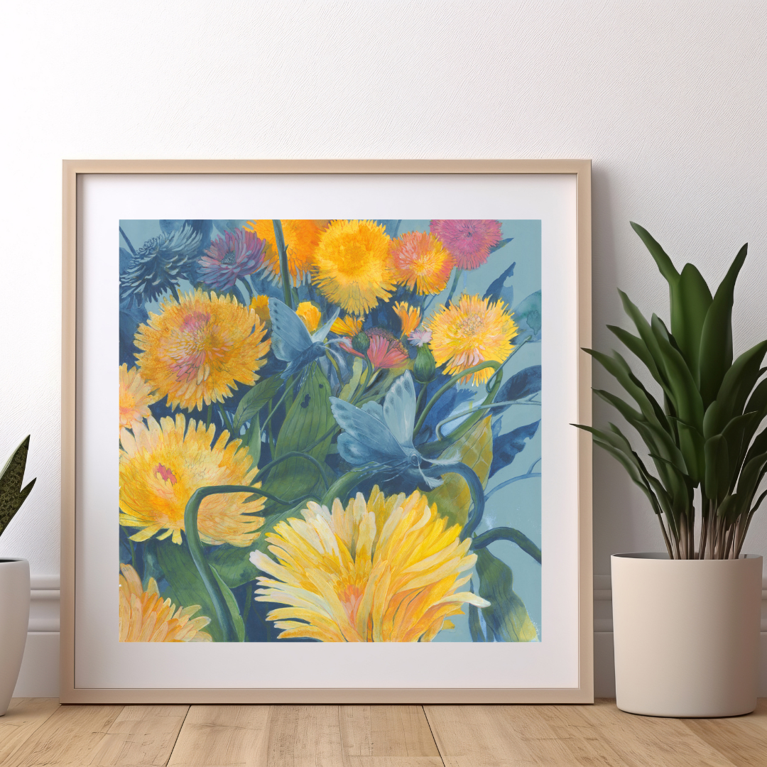 An art print featuring bright blue moths flying through a yellow dandelion forest. It's framed in a modern wooden frame and sitting against a white wall between two potted plants.