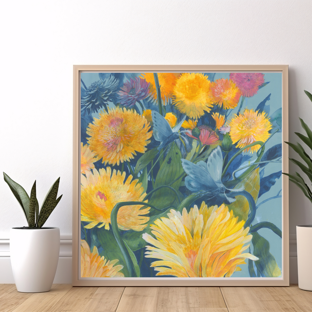 A square painting featuring two blue moths flying through a bright dandelion field. The painting is framed in a wood frame, sits against a white wall, and is flanked by two plants.