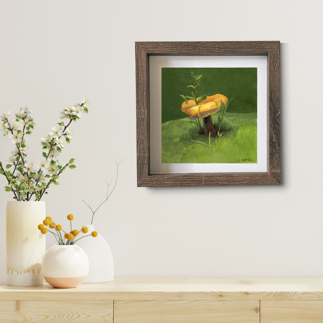 An art print featuring a golden wax cap mushroom in a brown frame in a modern living room.