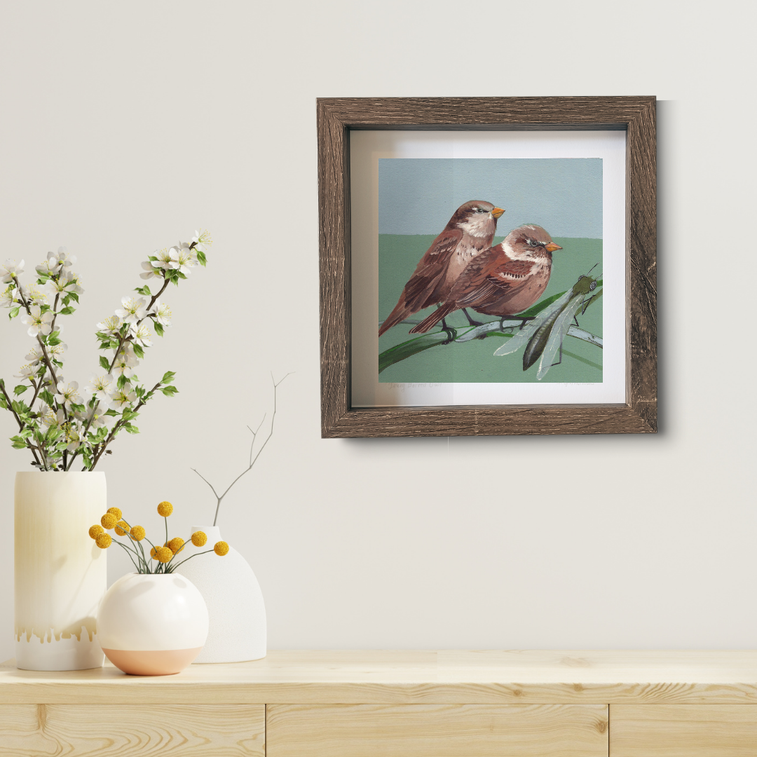 An art print featuring two house sparrows in a brown frame in a modern living room.