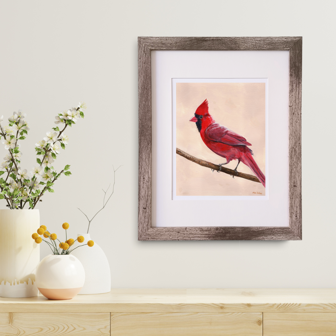 An art print featuring a bright red northern cardinal bird in a brown frame above a modern table.