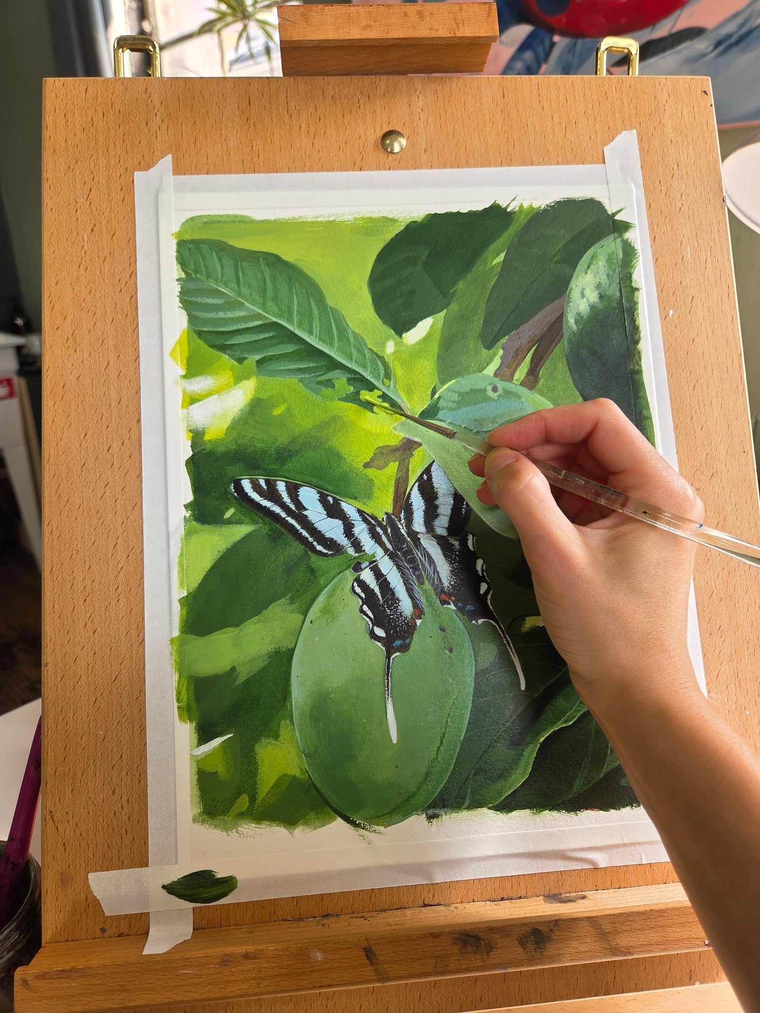 Person painting a butterfly on leaves with watercolors