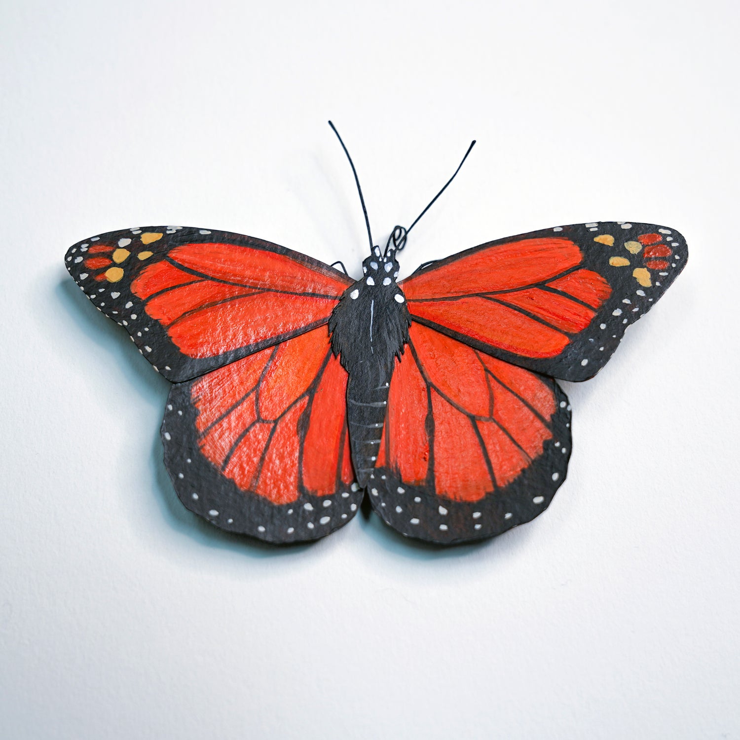 Monarch Butterfly art sculpture with red and black wings on a white background