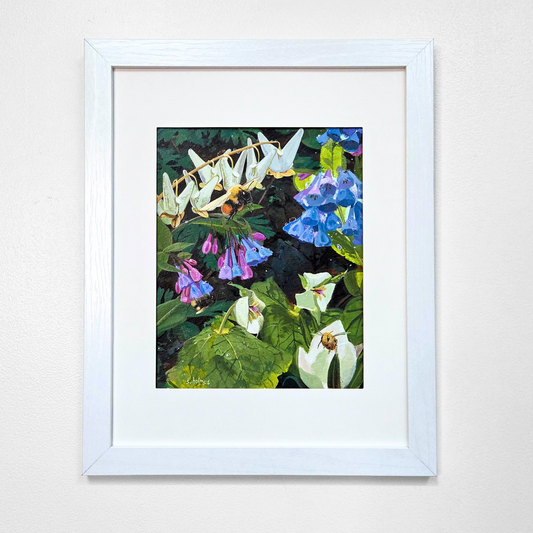 A framed floral art print featuring white, blue, and purple flowers with green leaves, presented in a white frame against a light gray wall.