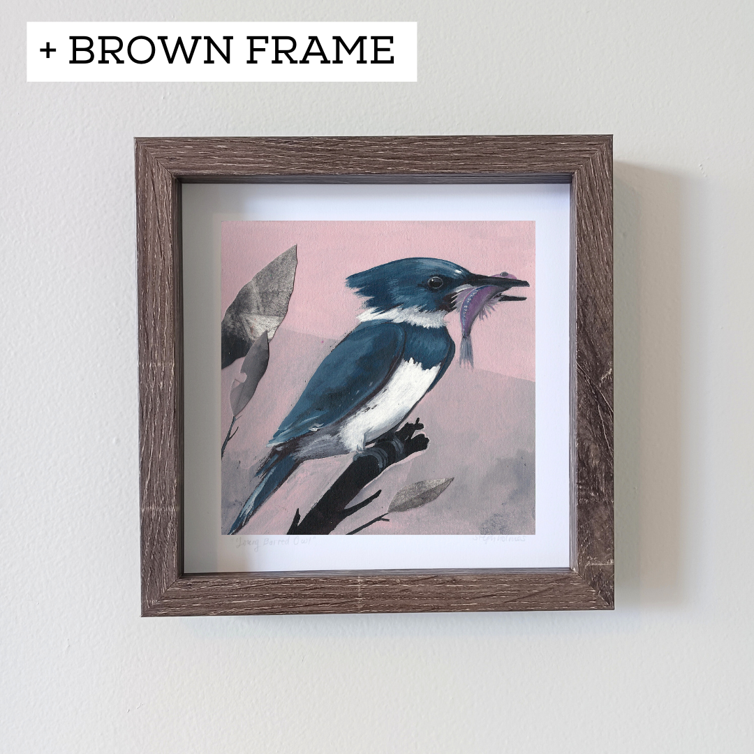 An art print featuring a blue Belted Kingfisher bird in a brown frame hanging on a white wall.