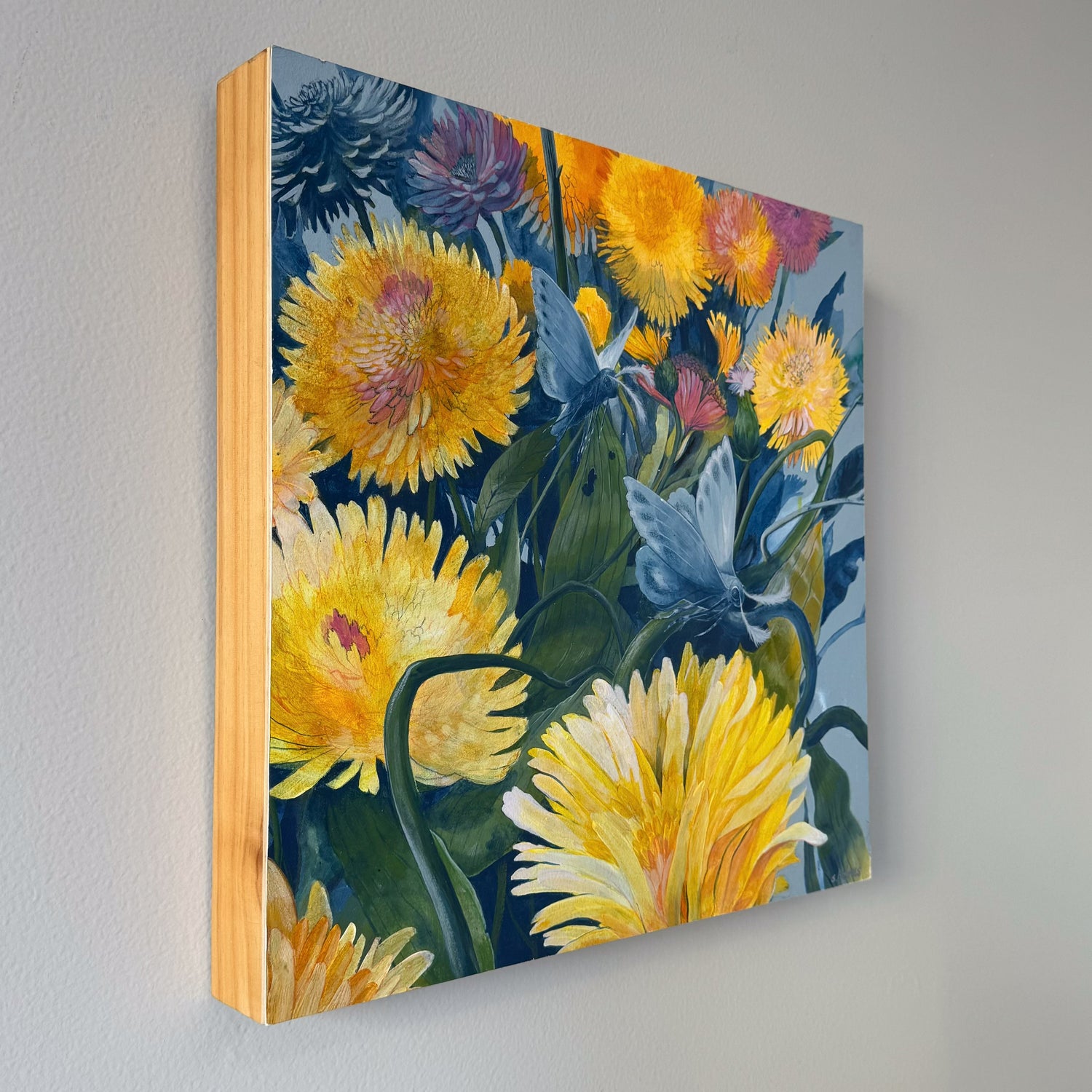 A square painting featuring two blue moths flying through a bright dandelion field. 