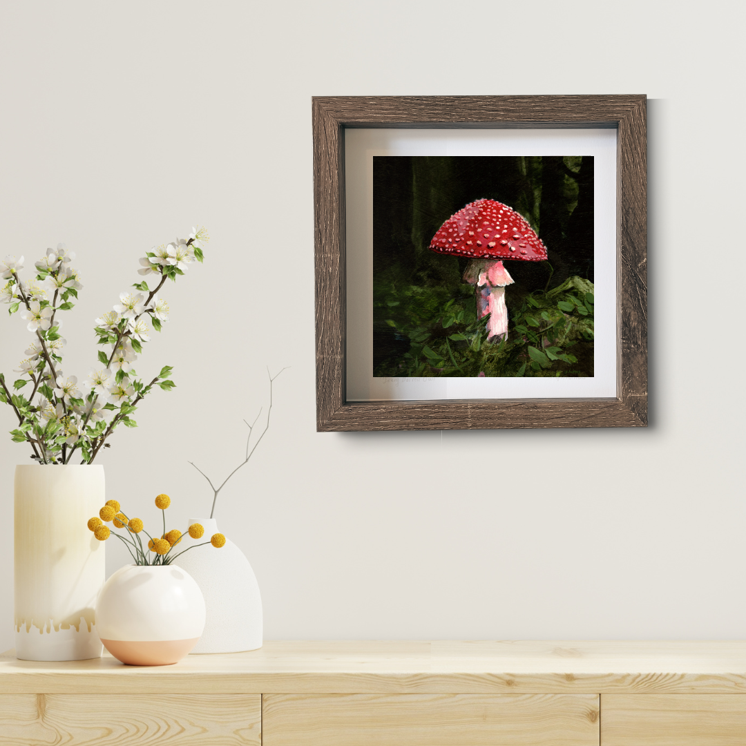 An art print featuring a red and white fly amanita mushroom in brown frame in a modern living room.